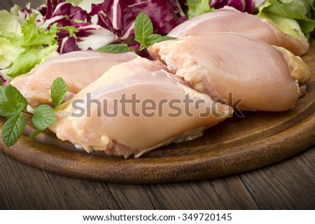 Fresh skinless chicken thighs and legs on cutting board