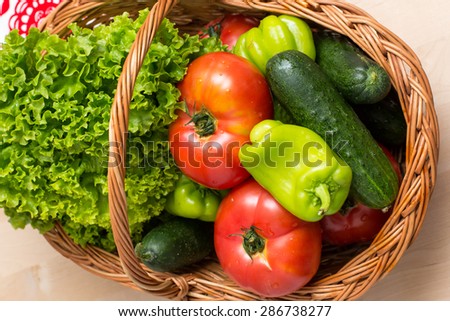 Fresh vegetables covered with water drops in basket. Organic Tomatoes, cucumber, pepper and vibrant green lettuce from the market. Fresh raw food.