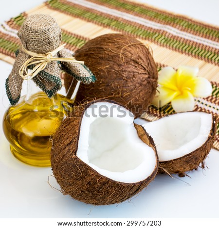 Still life with Half of Fresh coconut, bottle of coconut oil and flower
