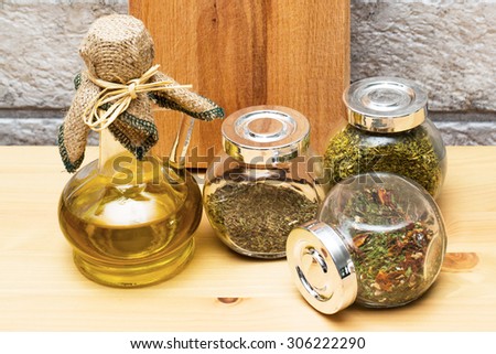 Still life with jug of olive oil, wooden cutting board and spices in the jars