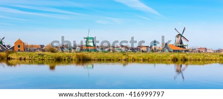 Panoramic view of windmill in Zaanse Schans, traditional village in Holland, reflection in lake, blue sky, copy space