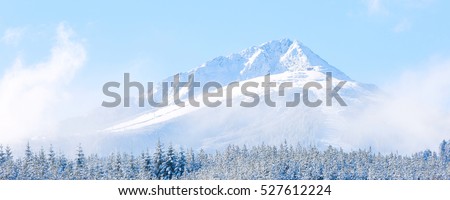 travel ski resort background with ski slopes panoramic view, snow mountain peak, fog and blue sky