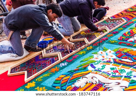 ANTIGUA, GUATEMALA - APRIL 1, 2012: Making a Holy Week carpet (or alfombra) in the path of a religious procession using wooden stencils and dyed sawdust