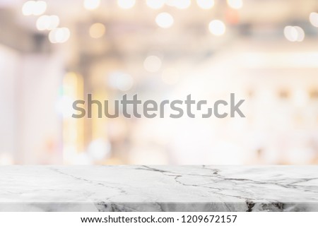 Empty white marble stone table top on blurred with bokeh shopping mall interior background - can be used for display or montage your products
