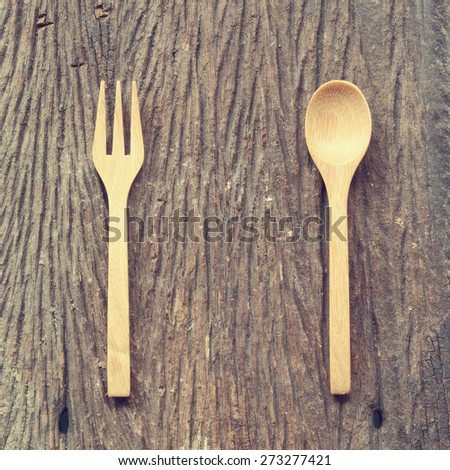 Wooded spoon and fork on old wood background with vintage filter