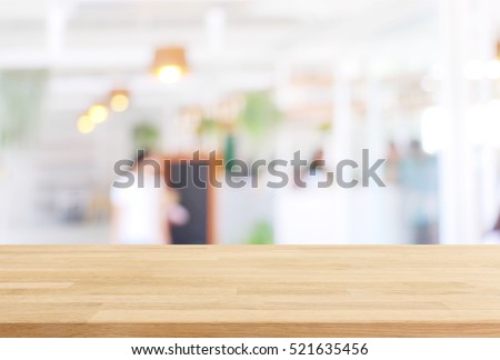 Wood table top and blurred restaurant interior background with vintage filter - can used for display or montage your products.
