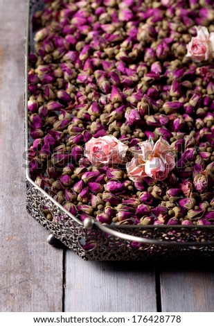 Dried roses and rose buds in a vintage tray on a wooden background
