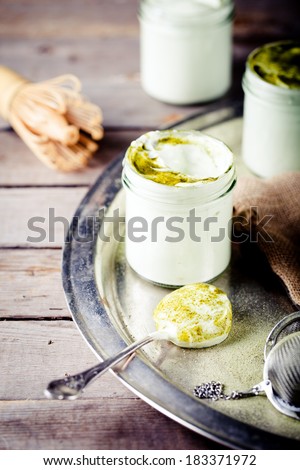 Green tea matcha yogurt, dessert, mousse in a glass jar on a metal vintage tray on a wooden background