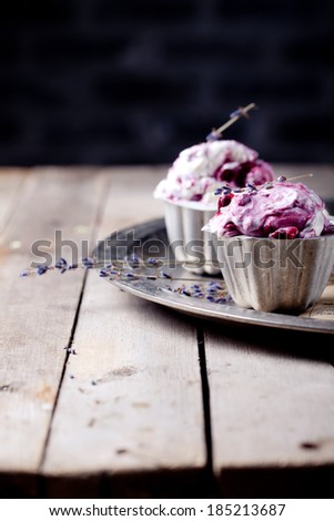 Berry ice cream in vintage metal cups on a old metal tray with lavender flowers on a wooden background