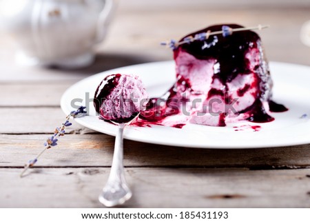 Berry ice cream with topping on a white plate with spoon on a wooden background