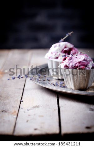 Berry ice cream in vintage metal cups on a old metal tray with lavender flowers on a wooden background