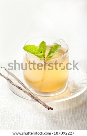 Glass cup of a herbal tea with fresh mint leaves and vanilla pods