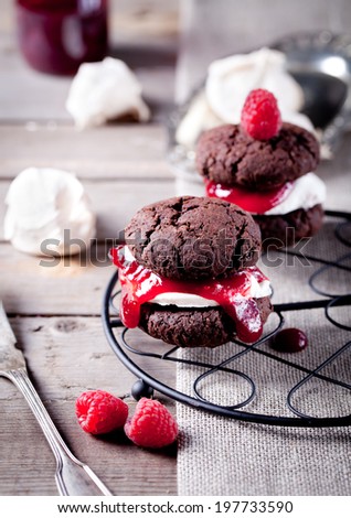 Chocolate cookie sandwich with a raspberry jam and meringue