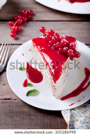 Traditional crepe cake with custard cream and fresh berry topping on a wooden background