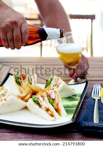 Club sandwich with french fries and  a glass of beer on a wooden table. Fast food.