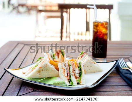 Club sandwich with iced soda drink on a wooden table. Fast food.