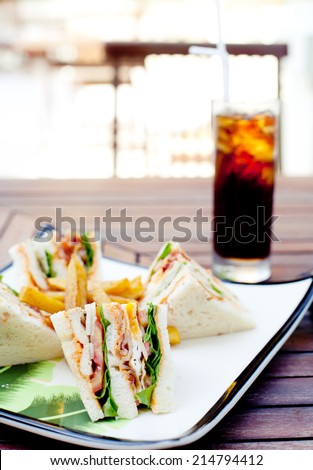 Club sandwich with iced soda drink on a wooden table. Fast food.