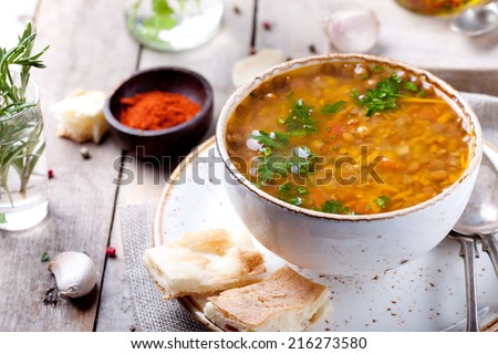 Lentil soup with smoked paprika and bread in a ceramic bowl on a wooden background