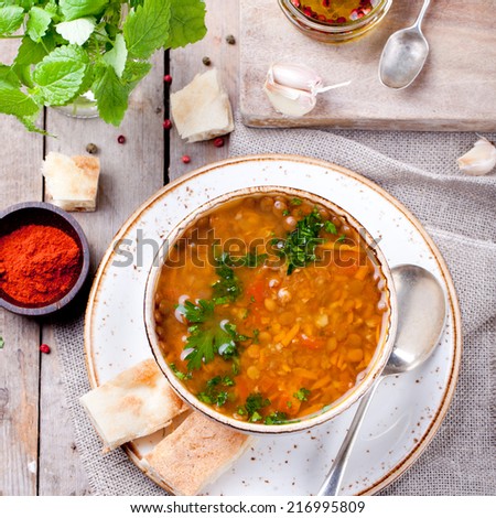 Lentil soup with smoked paprika and bread in a ceramic bowl on a wooden background
