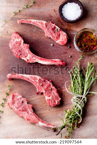 Raw meat, mutton, lamb rack with fresh herbs on a wooden background