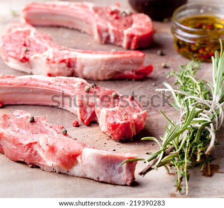 Raw meat, mutton, lamb rack with fresh herbs on a white paper background