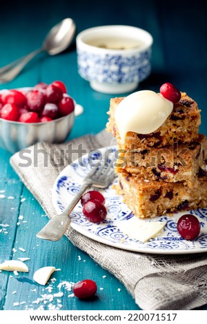 White chocolate brownie with cranberry and coconut on a white and blue wooden background