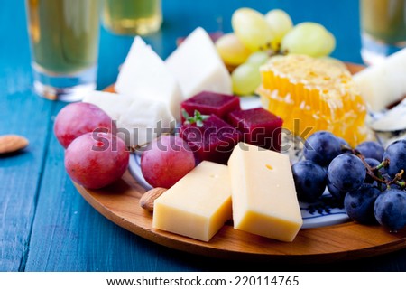 Cheese plate with fresh grape, honey comb, nuts and plum jelly, marmalade on  a blue wooden background