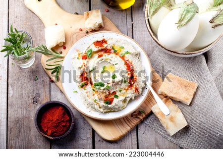 Traditional arabian eggplant dip baba ganoush with herbs and smoked paprika on a wooden background