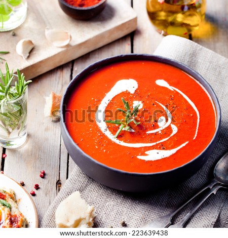 Tomato, red pepper soup, sauce with olive oil, rosemary and smoked paprika on a wooden background.