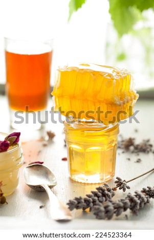 Honey variety with bee\'s comb in a glass jars with flowers and fresh herbs.