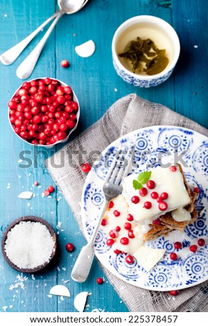 White chocolate cake, brownie with cranberry and coconut on a white and blue wooden background