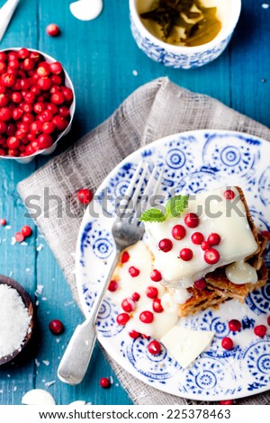 White chocolate cake, brownie with cranberry and coconut on a white and blue wooden background