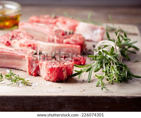 Raw meat, mutton, lamb rack with fresh herbs on a white paper background.
