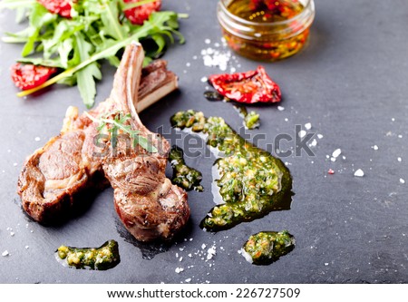 Grilled meat, mutton, lamb rack with fresh salad and sauce on black stone plate. Copy space