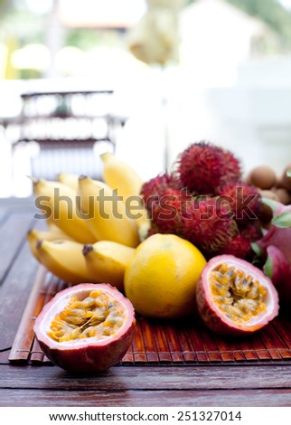 Assortment of tropical exotic fruits: dragon fruit, bananas, passion fruit, longan, rambutan on a wooden background