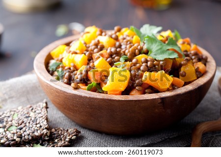 Lentil with carrot and pumpkin ragout in a wooden bowl on a wooden background