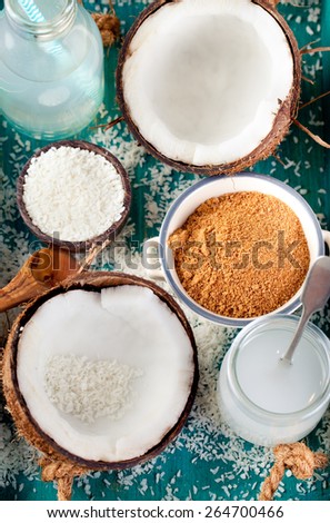 Coconut with coconut oil, water and sugar and coconut flakes on a wooden turquois background