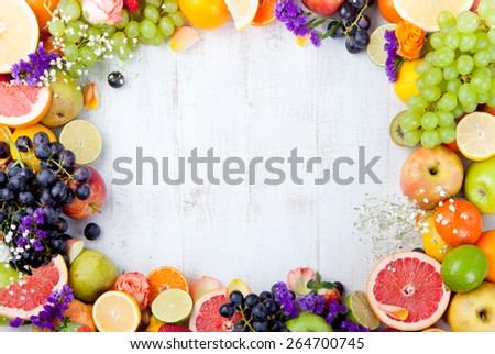 Fruits, berries and flowers frame, white wooden background. Copy space.