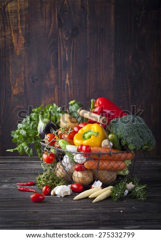 Vegetables variety in a wire basket on a wooden background. Copy space