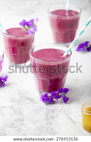 Blueberry, blackberry, honeysuckle, honeyberry smoothie with violet syrup and acai berry powder on a stone background.