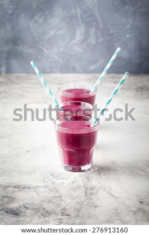 Blueberry, blackberry, honeysuckle, honeyberry smoothie with violet syrup and acai berry powder on a stone background. Copy space