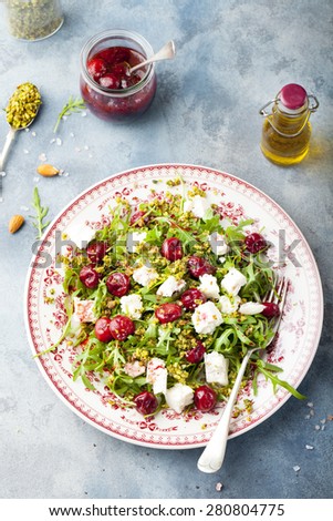 Salad with arugula, cherries and goat cheese on a blue background