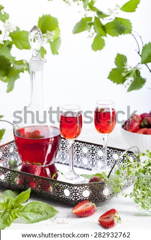 Strawberry and basil homemade liquor on a white background with green leaves and flowers