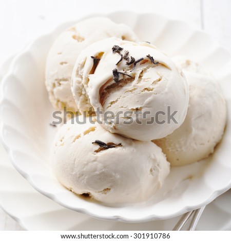 Ice cream with Earl grey tea flavor in white ceramic bowl on a white wooden background