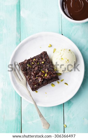 Vegan lentil brownies , gluten free, with pistachio ice cream on a white plate on a turquoise background