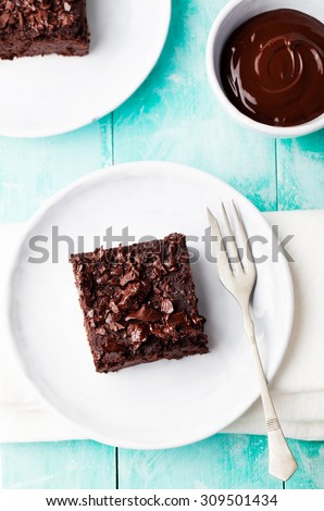 Chocolate brownie, cake on a white plate on a turquoise wooden \
background