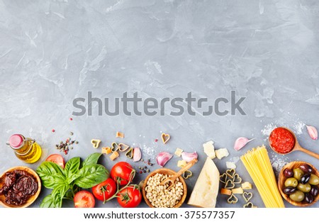 Italian food background with vine tomatoes, basil, spaghetti, olives, parmesan, olive oil, garlic Ingredients on stone table Copy space Top view