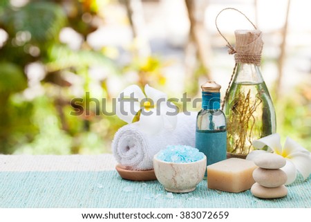 Spa and wellness massage setting Still life with essential oil, salt and stones Outdoor summer background Copy space