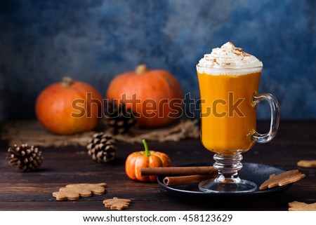 Pumpkin spice latte, smoothie with whipped cream on top on a wooden background. Copy space