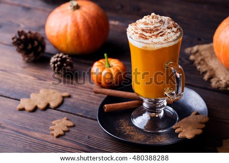 Pumpkin smoothie, spice latte. Boozy cocktail with whipped cream on top on a wooden background